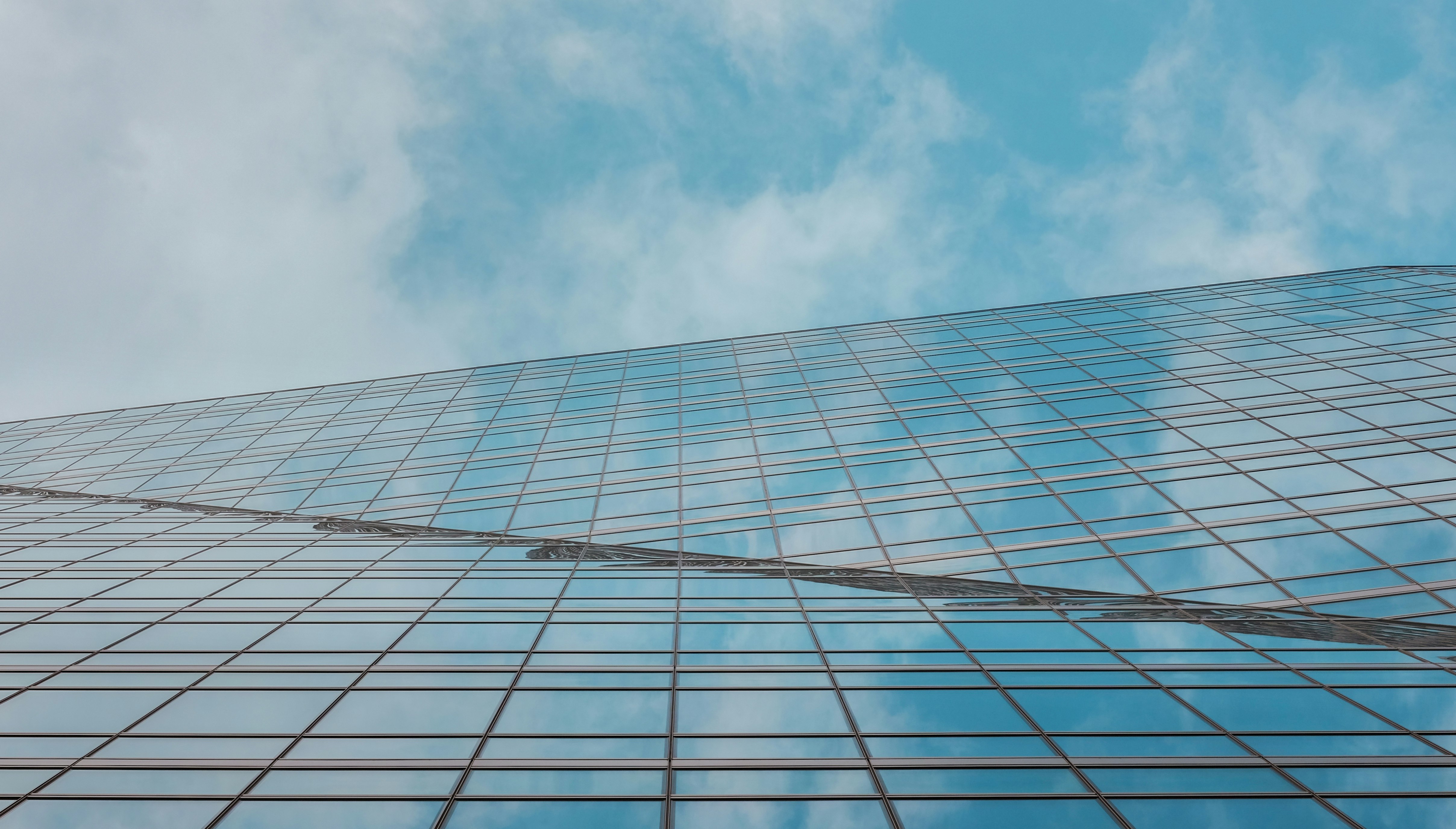 blue and white glass walled building under blue and white cloudy sky during daytime